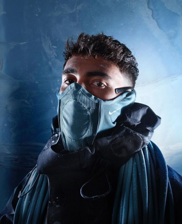 Portrait d'Inoxtag, le visage couvert d'un masque de protection, sur fond de glace.