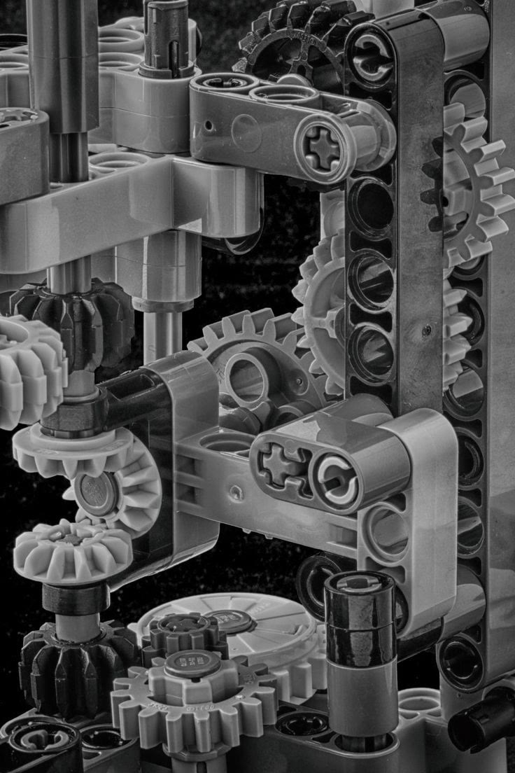 Un mécanisme Lego Technic gris et noir : engrenages, cardan et crémaillère dans un châssis étroit.