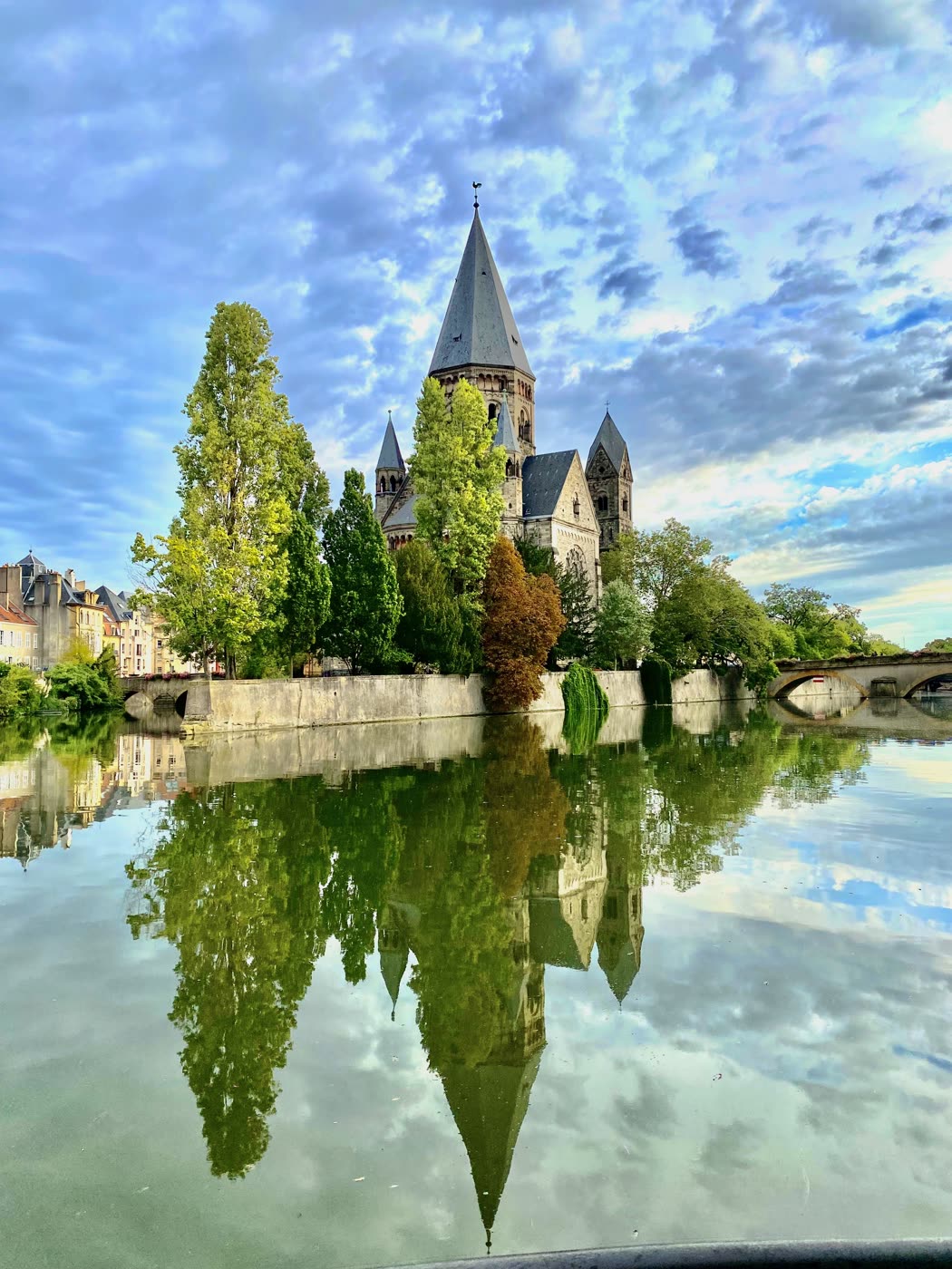 Une église sur une île, entourée d'arbres, reflétée dans la rivière.