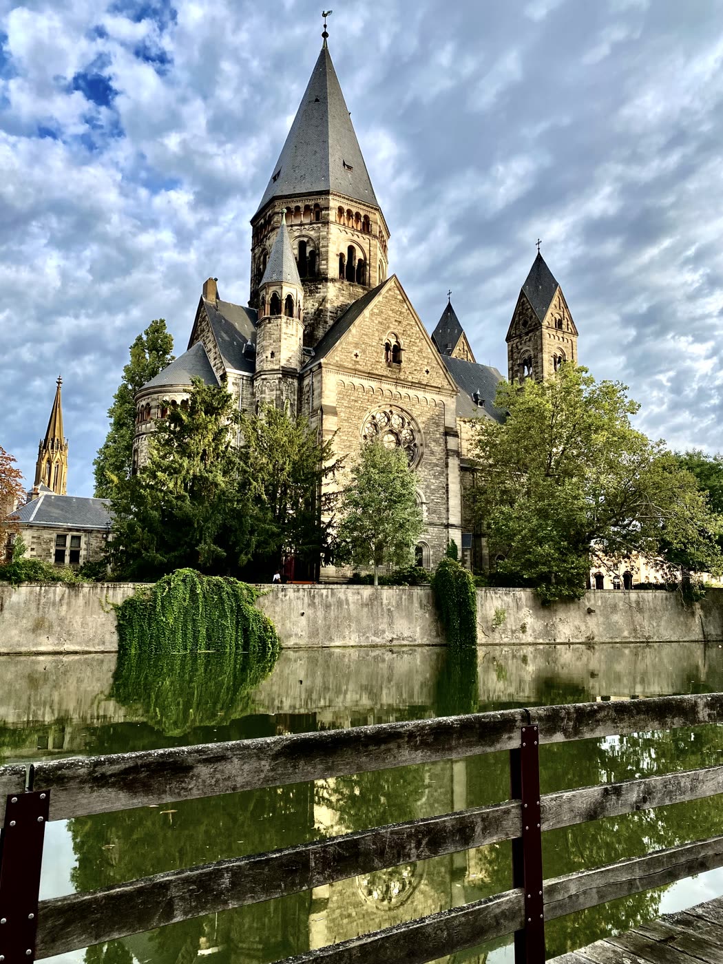 Une église sur une île, vue depuis une passerelle, reflétée dans l'eau.